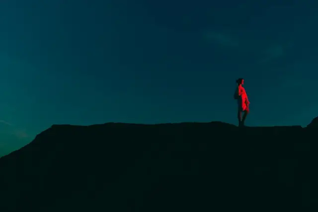 woman in a dark landscape lit by a red light